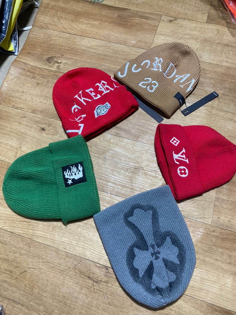 Brown Jordan 23 beanie displayed with red Lakers, green patch, red LV, and gray beanies on wooden floor.