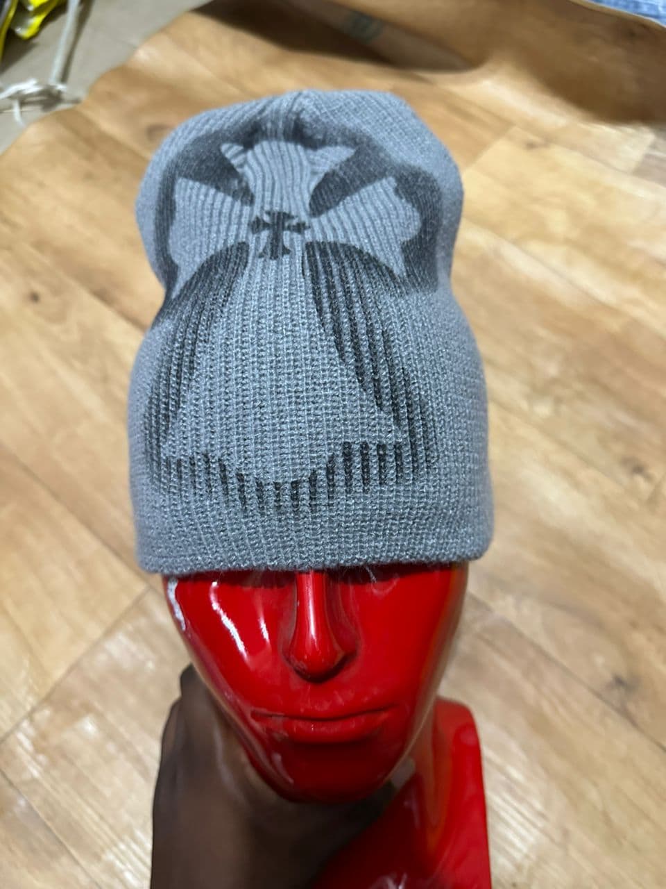 Gray cross motif beanie displayed on red mannequin head.