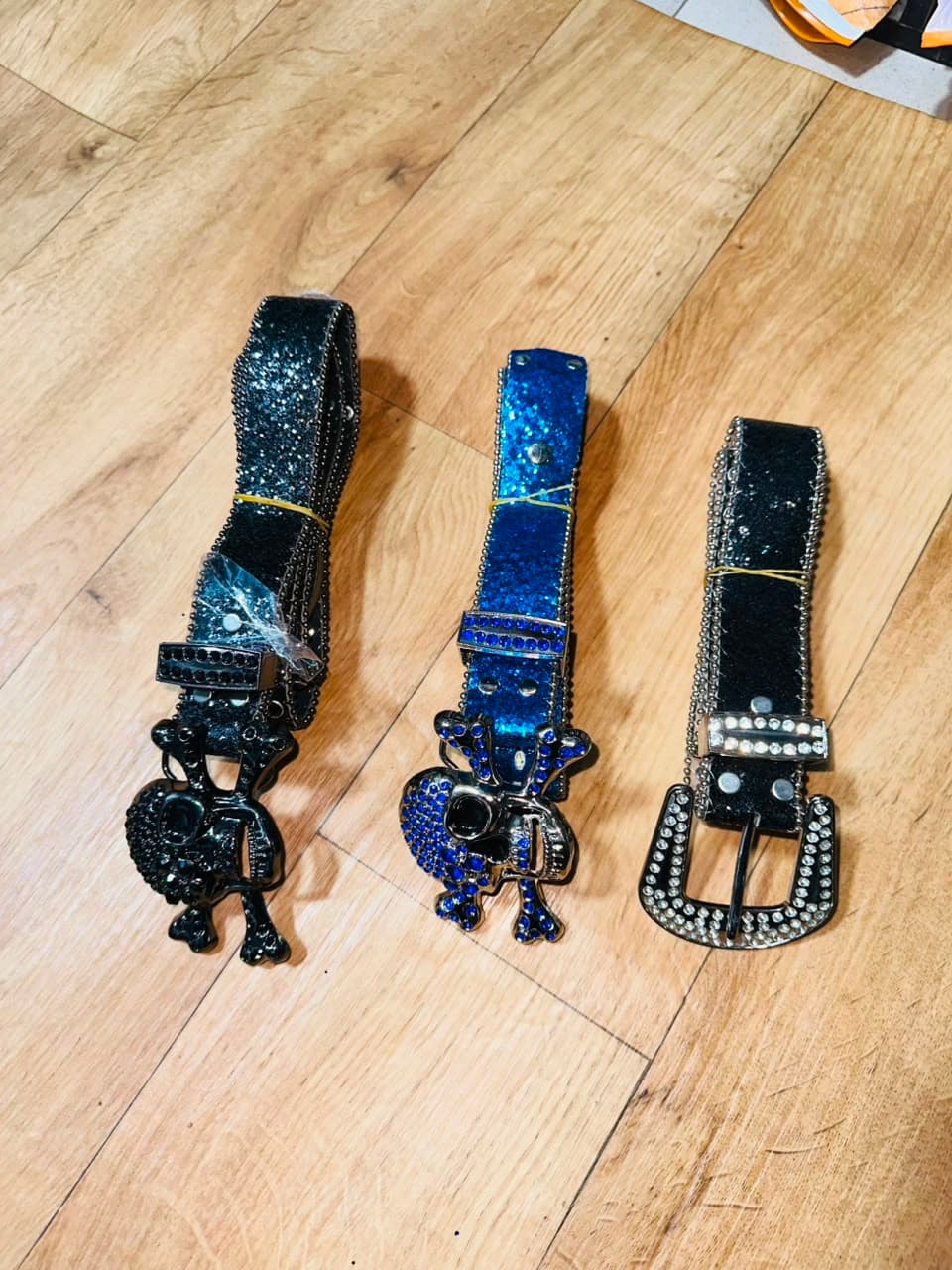 Rhinestone skull belts in black and blue with detailed buckles.
