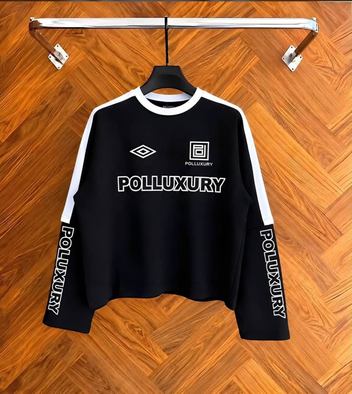 Black Polluxury cropped long sleeve top on hanger showing front with logos and prints.