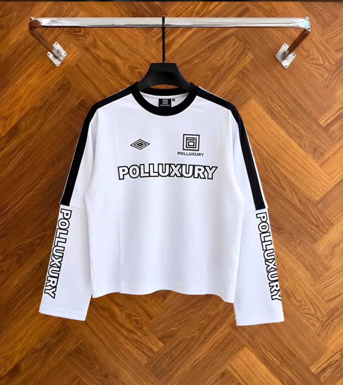 White Polluxury cropped long sleeve top on hanger showing front with logos and prints.