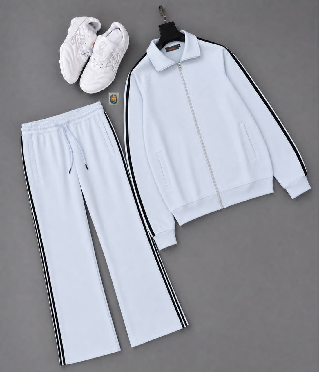 White track suit jacket and pants with black side stripes styled with white sneakers.