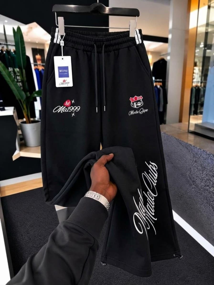 Gray SEVEERS striped joggers on hanger with hand holding leg to show emblem and SEVEERS logo.