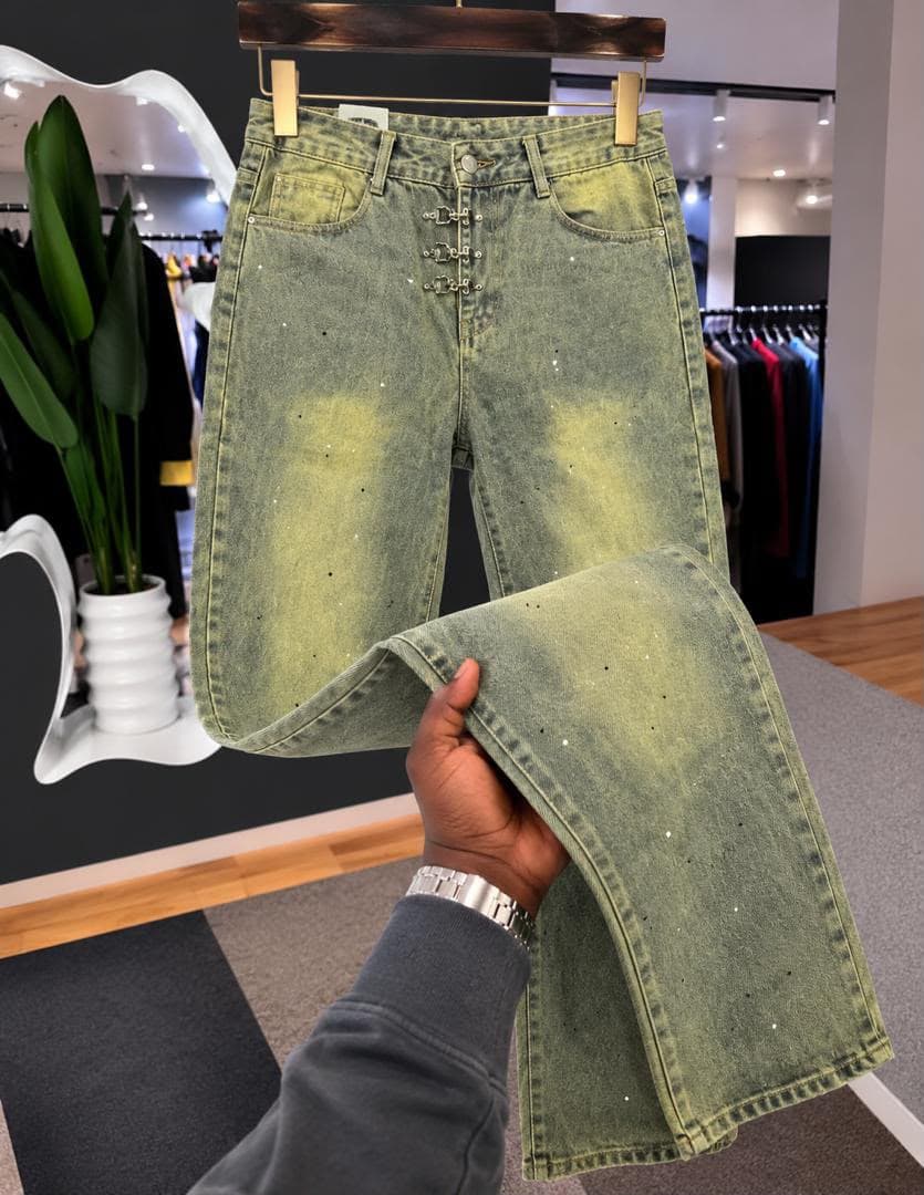 Flat lay of black baggy jeans with white eyelets on waistband and lower legs.