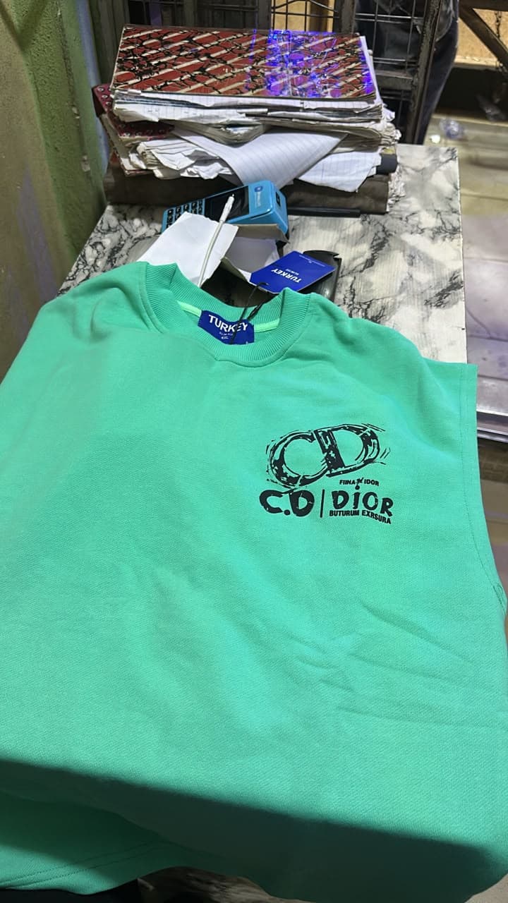 Mint green sleeveless tee with anime character holding guns graphic on front and 'I'M NOT WHO YOU THINK I AM' text print, shown on hanger and model.