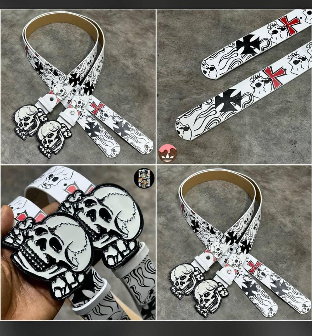 White skull and cross printed belt with large skull buckle shown in multiple views including on hand.