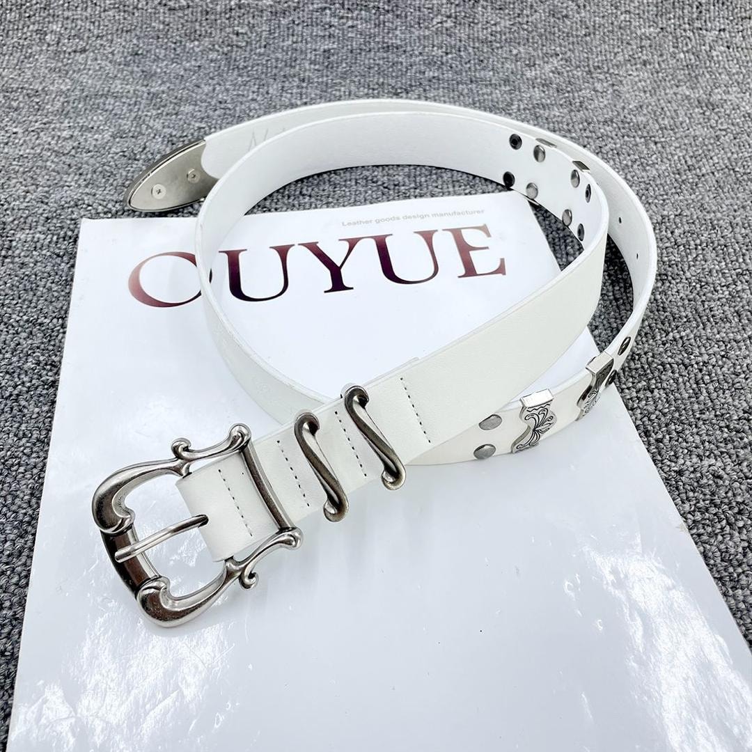 White leather belt with large ornate silver buckle and metal accents on white surface.