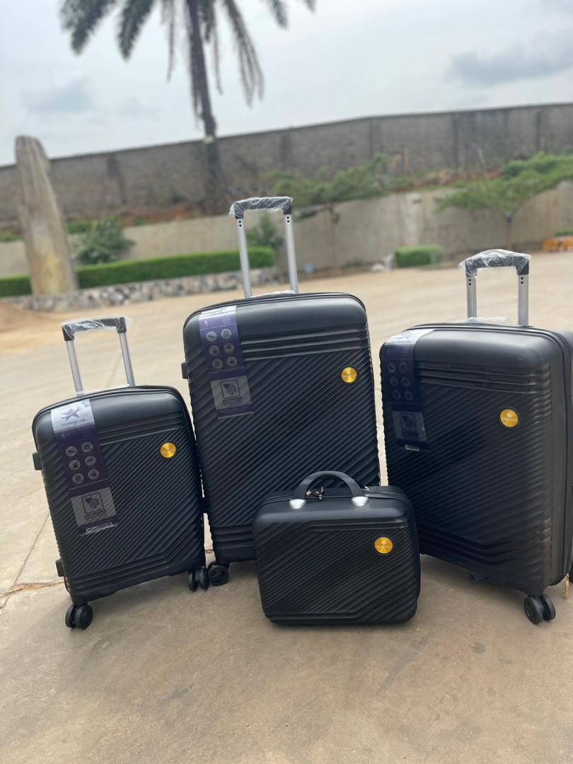 Black 4-piece diagonal textured luggage set with stickers shown outdoors.