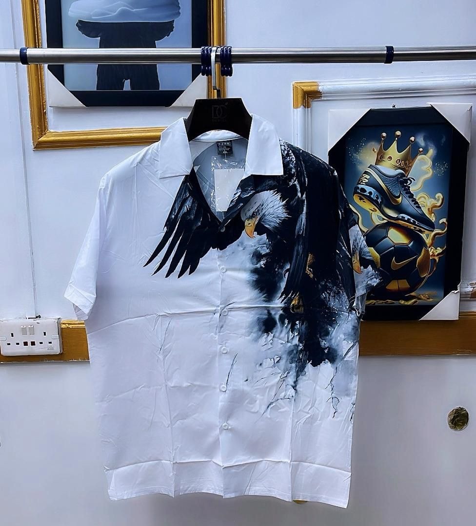 White short sleeve shirt with large eagle print hanging on rack.