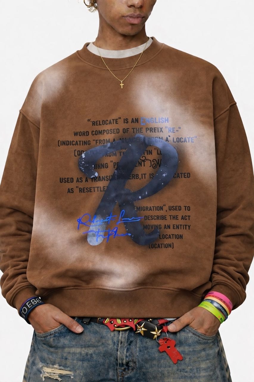 Model wearing brown bleached relocate graphic sweatshirt with hands in pockets.