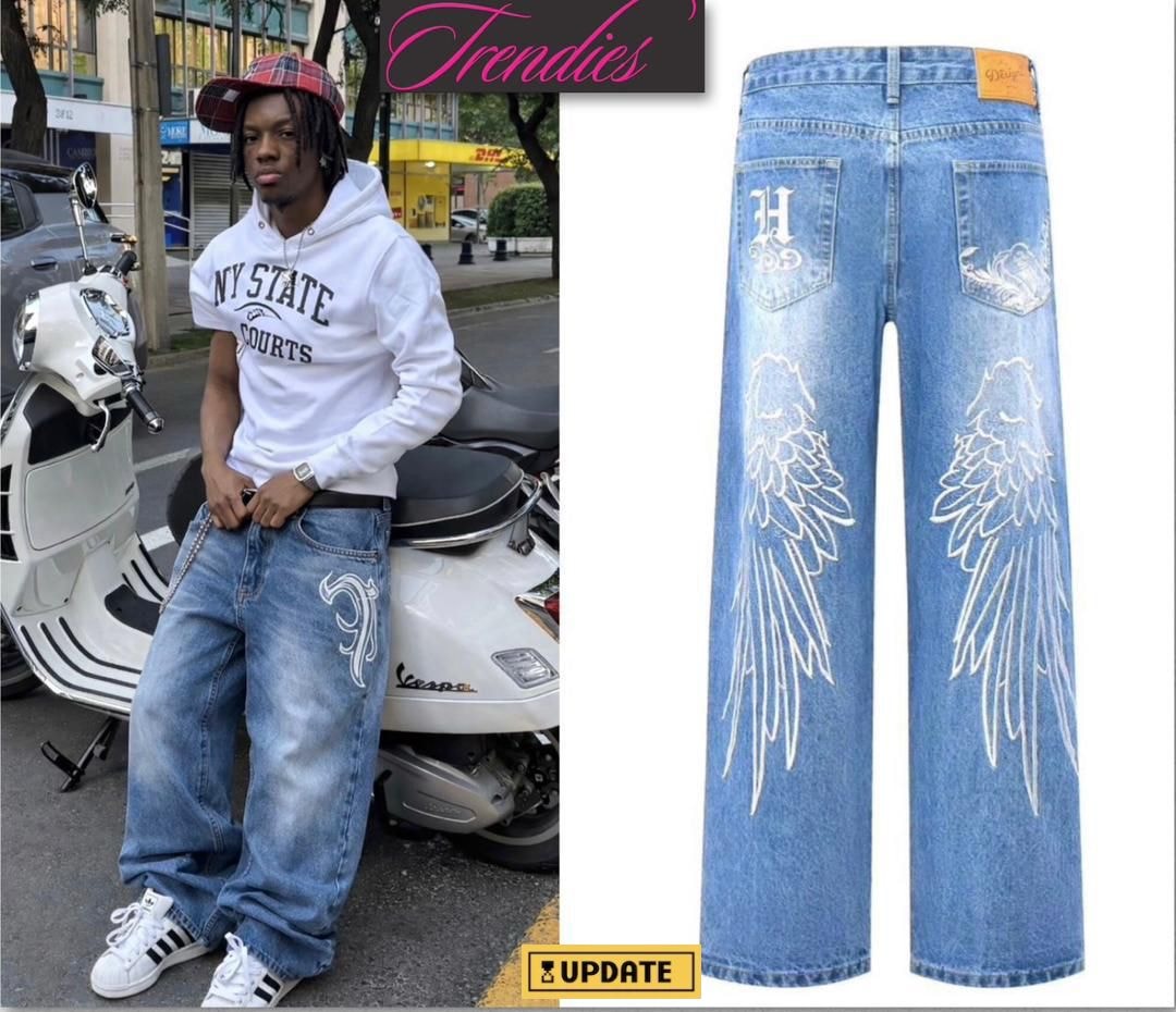 Light blue baggy jeans with white wing embroidery and designs on back pockets and legs.