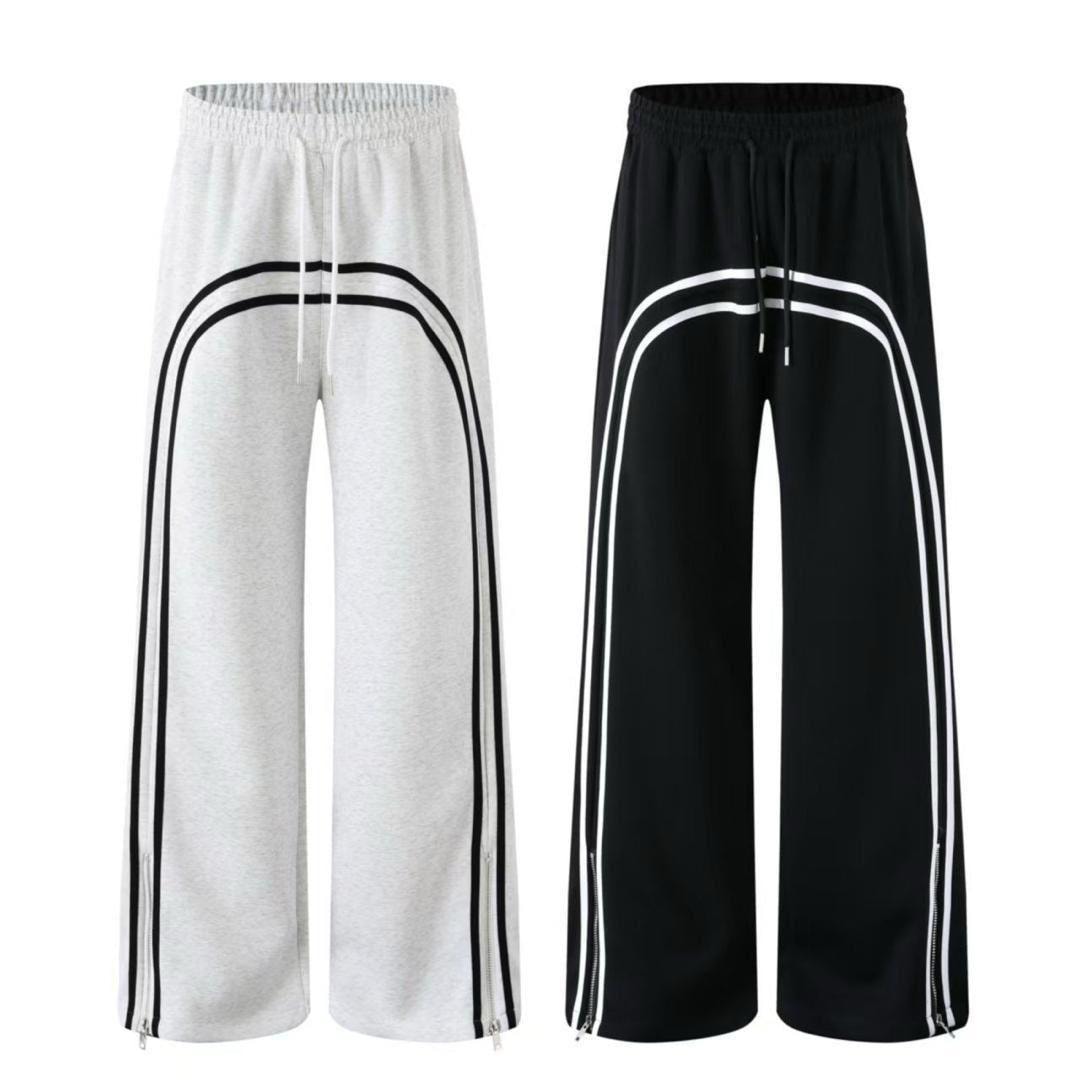 White and black curved stripe joggers with ankle zippers shown side by side.