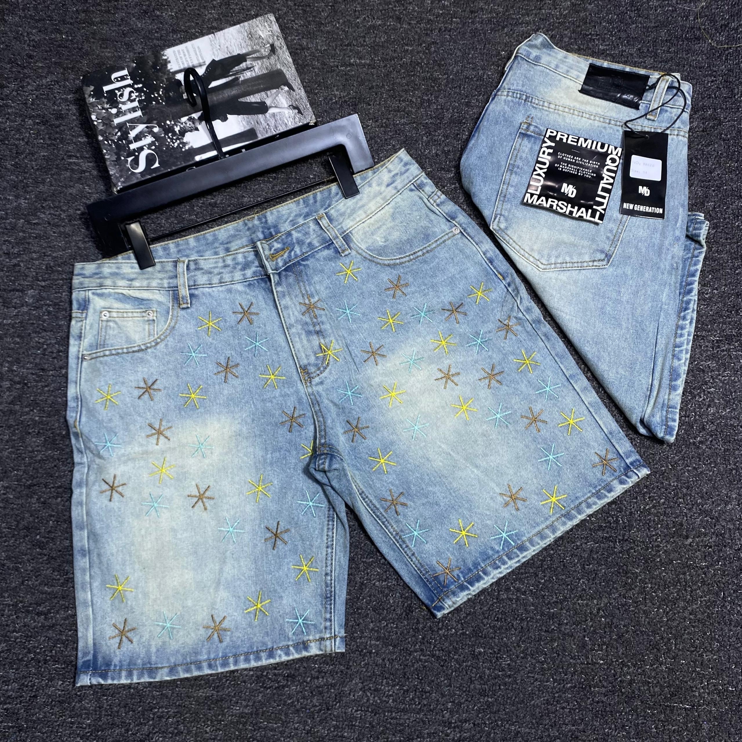 Flat lay of light blue star embroidered denim shorts with accessories and tags.