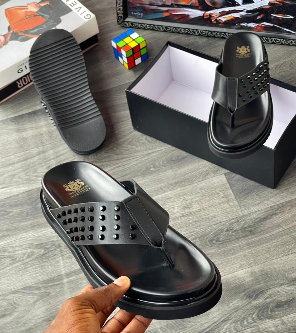 Black studded thong slide with platform sole and branding on insole.