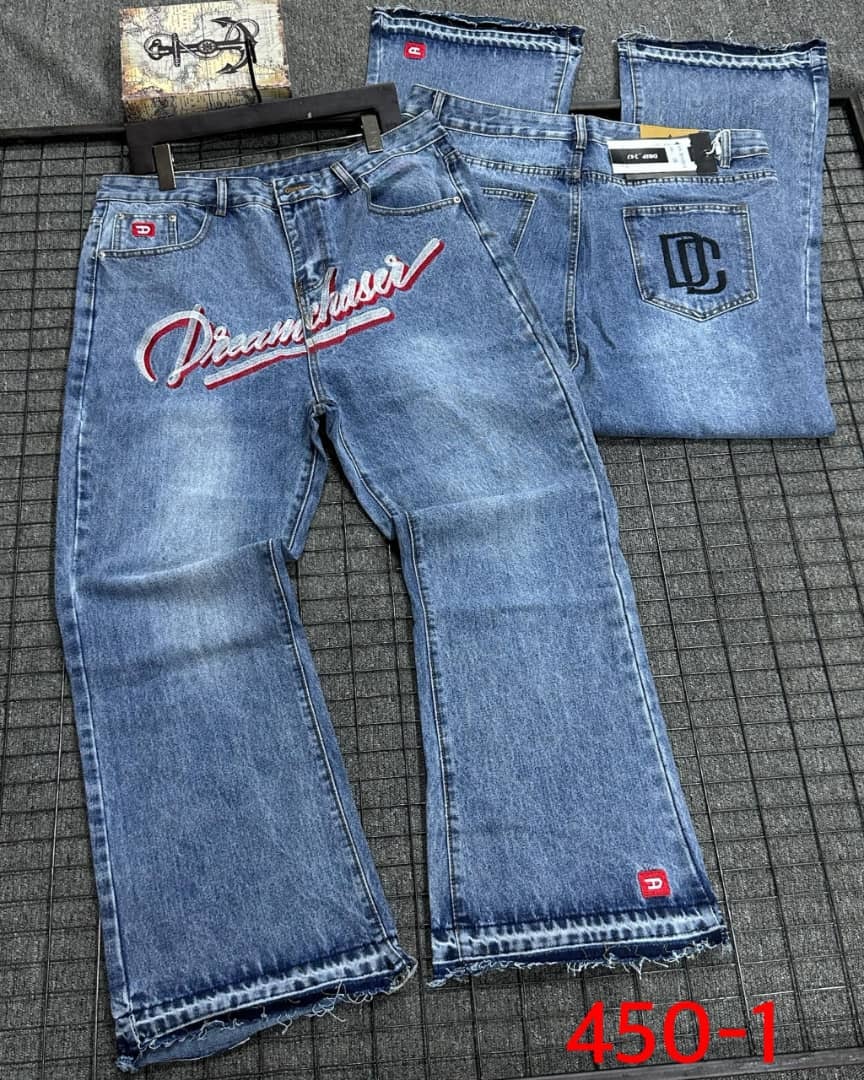 Flat lay of blue Dreamchaser baggy jeans showing front embroidery, back DC patch and frayed hems.