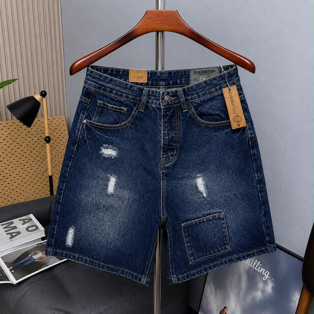 Dark blue denim cargo shorts with rips shown on wooden hanger.